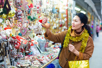 Portrait of happy asian woman choosing Christmas toys at Christmas market