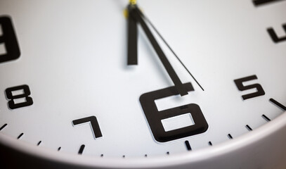 Wall clock show the time. A modern wall clock.  Close up to a wall clock, with black time pointer and red second pointer. Sun and sky reflecting in the watch during the time passing by