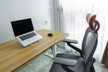 Ergonomic chair and Adjustable table with laptop computer in modern workplace. Good posture to...