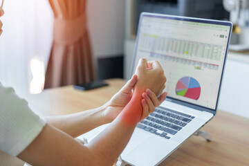 Woman having wrist pain when using laptop computer and mouse during working long time on workplace....