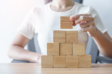 Woman hand placing wood block on the building. Leadership, Business process planning, Risk...