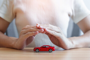 hand cover or protection red car toy on table. Car insurance, warranty, repair, Financial,...
