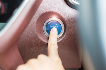 Finger press a car ignition button or START engine inside modern electric automobile. Keyless,...