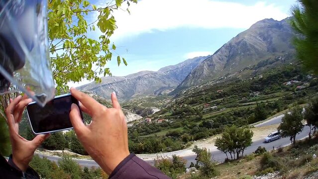 making video on phone pov, mountains on motorcycle pov, sun beams, beautiful landscape, amateur travel video