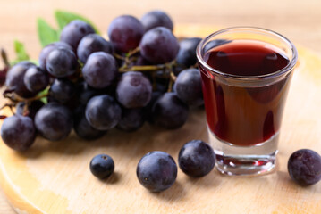 Black grape and juice in glass on wooden board, healthy drink