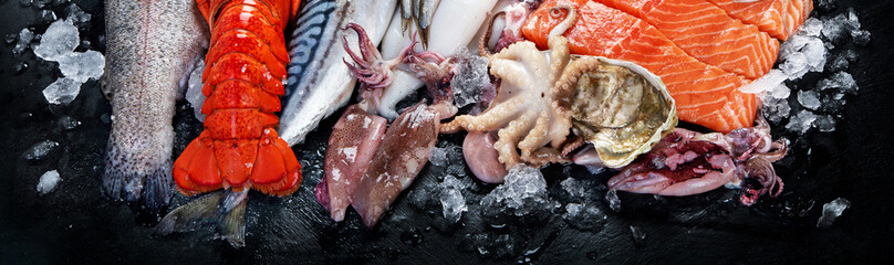 Fresh fish and seafood assortment on black background, fish market. Healthy diet eating concept....