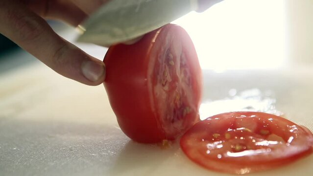 A sharp handcrafted Japanese Knife , slicing cleanly through a fresh tomato and other vegetables, skilled chef, slow video show casing a sharp Japanese knife 
