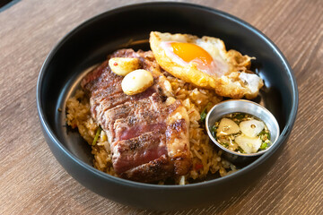 Wagyu beef with holy basil and chili fried rice served fried egg and fish sauce with Thai chilis. Top view on wooden table background.