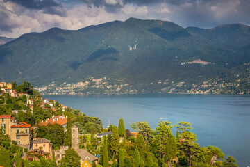 Idyllic Lake Como coastline with village and sailboat at dramatic sunset, Italy