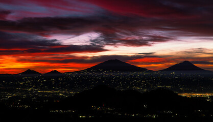 A beautiful colorful epic sunrise sky with mountain range and beautiful city lights - Magelang City and Merapi, Merbabu, Andong, Telomoyo mountain looking out from slope of Mount Sumbing