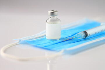 Medical vial of injectable medicine on a blue medical mask