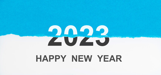 Torn blue paper with happy new year 2023 on white background