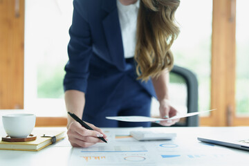 Portrait of a thoughtful Asian businesswoman looking at financial statements and making marketing plans using a computer on her desk