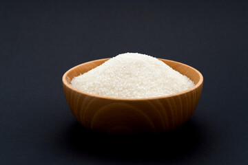 Granulated sugar in a bowl on black background