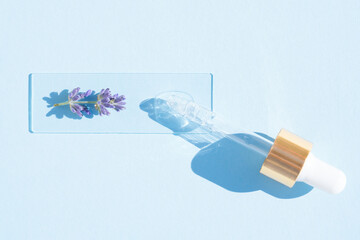 Pipette with cosmetic lavender oil over blue background. Texture of hydrolate or cosmetic oil with lavender extract for skin care. Selective focus