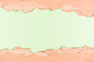 Frame made with sheets of corrugated cardboard over light green background as eco background with copy space for ecological project or paper packaging industry. Selective focus