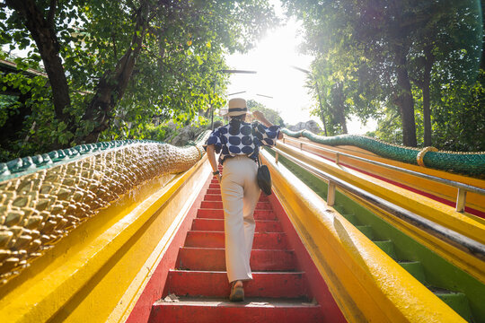 Asian Female Tourists Walking Up Colorful Stairs At Wat Tham Seua, Kanchanaburi, Thailand.