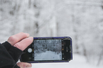 person holding a mobile phone on winter background. Using tech