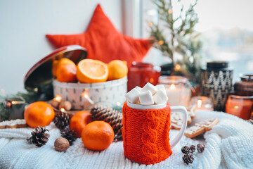 Beautiful Christmas still life. A cup of hot tea with a knitted sixth plaid on the windowsill with New Year's decor