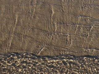 A transparent sea wave running over the sand