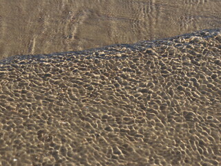 A transparent sea wave running over the sand