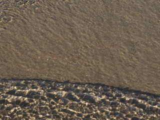 A transparent sea wave running over the sand