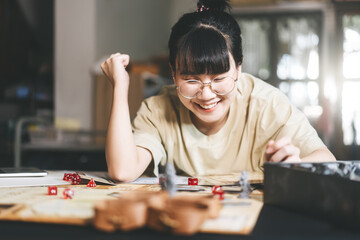 Young adult asian woman enjoying role playing tabletop storytelling and board game with miniatures