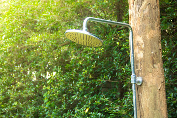 Outdoor shower head stick on the wooden  in the garden.