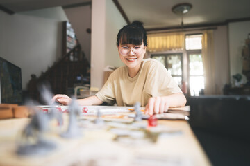 Young adult asian woman enjoying role playing tabletop storytelling and board game with miniatures