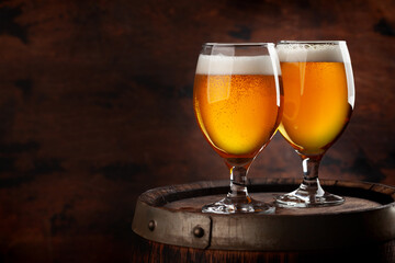 Two beer glasses on wooden barrel