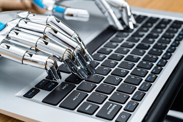 Robot hand typing on laptop