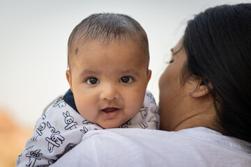 cute infant facial expression resting at mother shoulder from flat angle