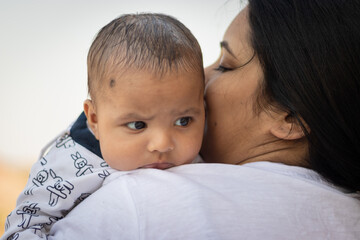 cute infant facial expression resting at mother shoulder from flat angle