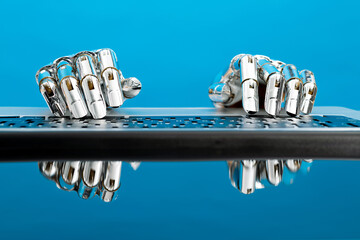 Robot hand typing on laptop