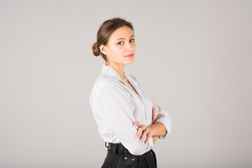 Portrait of a businesswoman with folded hands on a gray background.