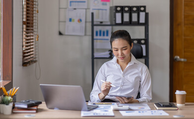 Business Asian woman using calculator and laptop for doing math finance on an office desk, tax, report, accounting, statistics, and analytical research concept