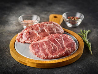 Fresh raw pork cheeks with salt and pepper. Grey background