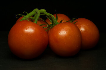 Red tomatoes on black background. Dark mood style.