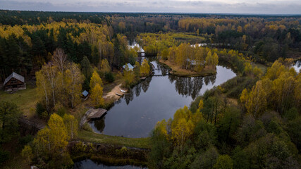 panoramic view from a drone on the edge of the forest with wooden houses and a river against the backdrop of autumn nature