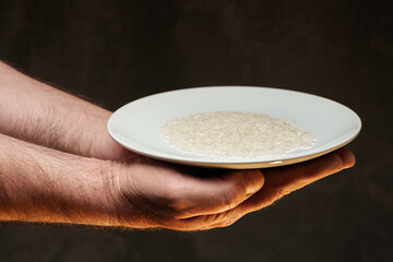 Hands holding a heap of dry rice grain on black background