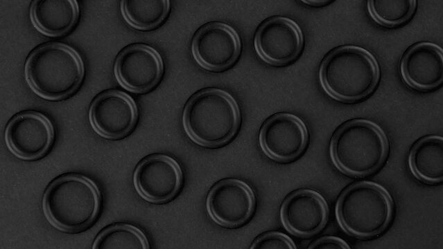 Abstract top view of black round rubber seal gaskets. Geometric shapes details close-up. Rotation