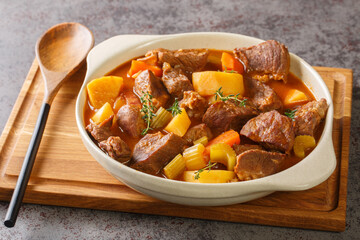 Hearty Irish inspired beef stew made with garlic, stock, Guinness, bacon, potatoes, carrots, and onions closeup in the pot on the table. Horizontal - obrazy, fototapety, plakaty