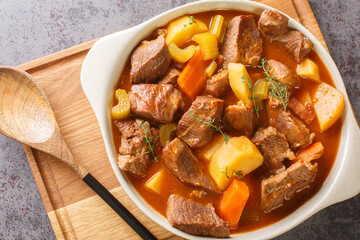 Traditional Irish stew of meat and vegetables in a thick sauce based on dark beer close-up in a pot on the table. Horizontal top view from above