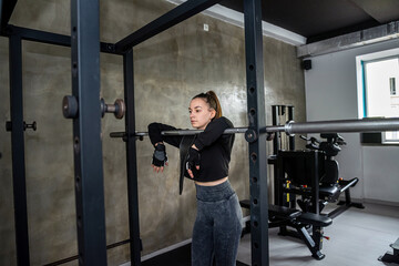 Fototapeta na wymiar girl practices strength exercises with a new simulator in a spacious gym to lose extra pounds.