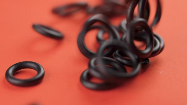 Sealing rubber gaskets falling on a colored orange background in slow motion close-up. Hydraulic spare parts. Rotation