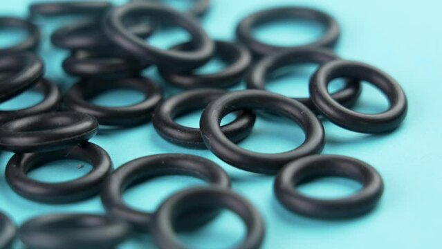 Black sealing rubber gaskets on colored blue background. Hydraulic spare parts. Rotation. Macro