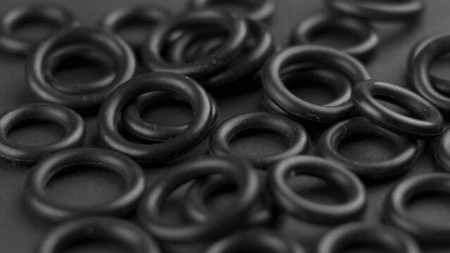 Sealing rubber gaskets on dark black background. Hydraulic spare parts. Rotation. Macro