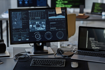 Background image of several computer screens with data and control panels on desk in IT company office