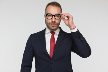 handsome businessman arranging his eyeglasses and wearing a nice suit
