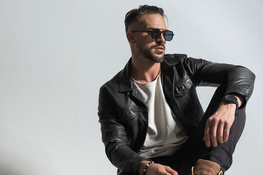 fashion modern man in leather jacket with sunglasses looking to side